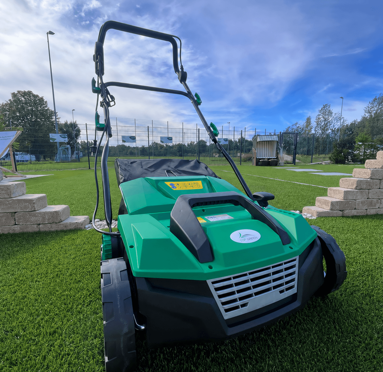 Cepillo y máquina de limpieza para césped artificial TOP GREEN sobre una superficie de césped artificial