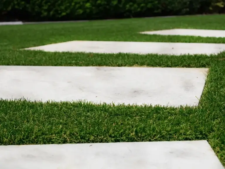 Kunstrasen mit Steinplatten im Garten – TOP GREEN Referenz